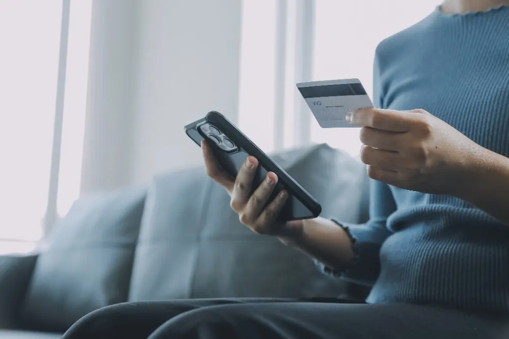 Personne réglant sa facture en ligne avec sa carte bancaire et son smartphone